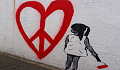 young girl painting a huge heart with a peace symbol inside