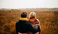 Paar mit Blick auf ein kahles Grasfeld