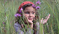 giovane ragazza in un campo di erbe alte e fiori di campo