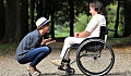 persona cariñosa en cuclillas frente a otra en silla de ruedas