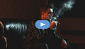 jeune homme assis dans une pièce sombre, fumant