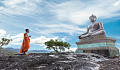 statua di buddha con un giovane monaco in piedi di fronte