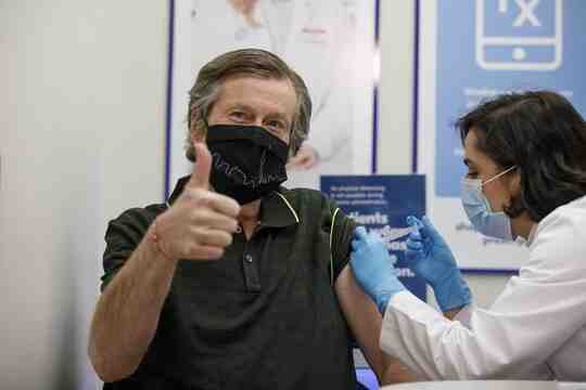 John Tory recebendo uma injeção, dando um sinal de positivo