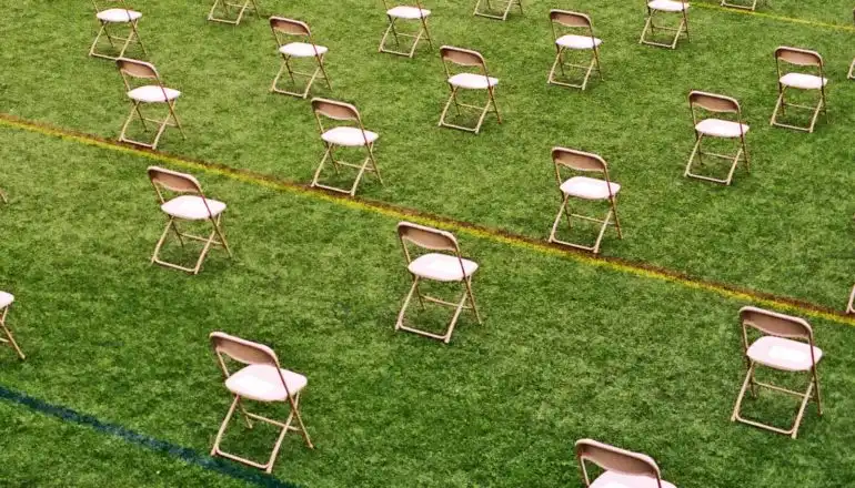 เก้าอี้นั่งห่างกันหกฟุตบนสนามสีเขียว