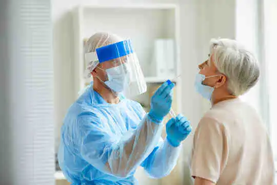 Un lucrător medical efectuează un test de tamponare COVID pe un pacient.