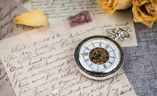 a pocket watch resting on a hand-written letter
