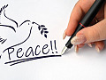 en hand som skriver ordet Peace och ritar en duva som håller i en olivkvist
