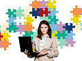 nő kezében egy laptop, a háttérben a puzzle darabjai a falon a háta mögött