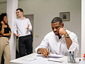 arka planda konuşan iki iş arkadaşıyla masasında oturan bir adam