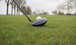 un gros plan d'un club de golf placé juste en face d'une balle de golf