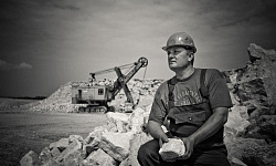 איש יושב מחזיק סלע גדול באתר בנייה