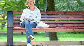mosolygós nő ül egy nyilvános padon