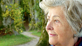 seorang wanita tua berdiri di luar melihat sesuatu di kejauhan
