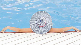 Les femmes portant dans la piscine avec ses bras sur le bord, portant un chapeau de soleil