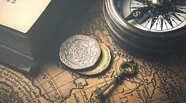 एक कुंजी की तस्वीर, एक कम्पास, सिक्के, एक पुराने नक्शे पर ओवरले