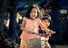 Молодая девушка на велосипеде с братом, сидящим позади нее
