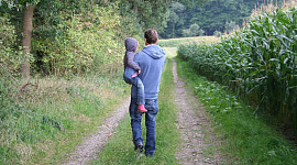 father holding son in his arms and walking down the road
