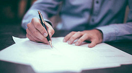 изображение человека, пишущего на листах бумаги