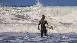 surfer cu o mică placă de surf cu față spre valuri imense