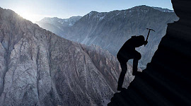 Foto silueta de alpinista con un pico para asegurarse