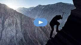 पर्वतारोही का फोटो सिल्हूट खुद को सुरक्षित करने के लिए एक पिक का उपयोग करता है