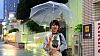 Mosolygó fiatal lány séta nyitott esernyővel