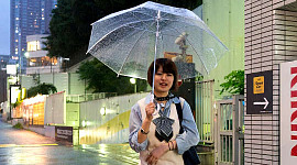 Hymyilevä nuori tyttö kävelee avoimen sateenvarjon kanssa