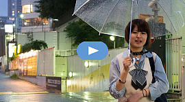 Hymyilevä nuori tyttö kävelee avoimen sateenvarjon kanssa