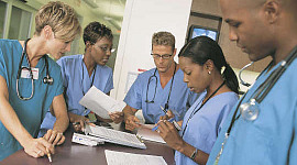 gruppo di operatori sanitari in piedi attorno a una scrivania o un tavolo