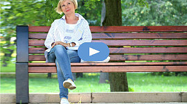 χαμογελαστή γυναίκα κάθεται σε ένα δημόσιο παγκάκι