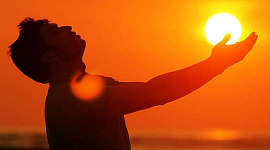 man outside with hands outstretched to the sun