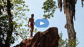 ένα νεαρό αγόρι που σκαρφαλώνει στην κορυφή ενός βράχου