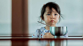 ulykkelig barn som sitter foran en skål med mat