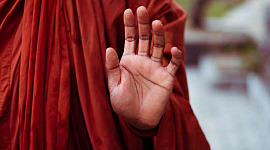 Monnik die een hand opsteekt in een mudra-gebaar