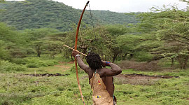 Arqueiro Hadzabe lançando uma flecha de seu arco