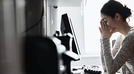 kobieta przy komputerze z rękami zakrywającymi twarz