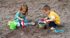 um menino e uma menina brincando na areia