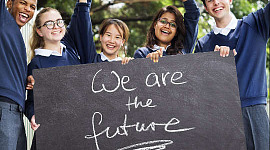 anak-anak sekolah memegang papan bertuliskan "We are the future"