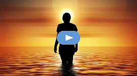 समुद्र में खड़ी महिला उगते सूरज को देख रही है