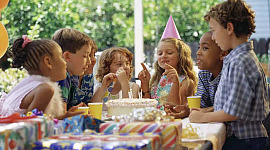 niños en una mesa alrededor de un pastel de cumpleaños