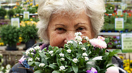 foto av en äldre kvinna med vitt hår bakom en bukett blommor