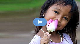 leende ung flicka som håller en oöppnad lotusblomma
