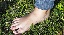 kuva ihmisen paljaasta jalasta seisomassa nurmikolla