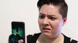 femeie privindu-și telefonul cu o expresie de dezgust pe față