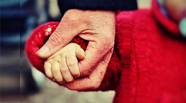 一個小孩走路，牽著她父親的手