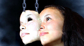 en mask som hålls upp av kedjor som överlappar en kvinnas ansikte