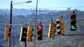 több közlekedési lámpa – az egyik piros, a másik zöld, két zöld nyíllal felfelé és jobbra