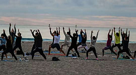 grupo de personas haciendo yoga en la playa
