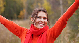 wanita muda tersenyum berpakaian merah dengan tangan terangkat tanda kemenangan