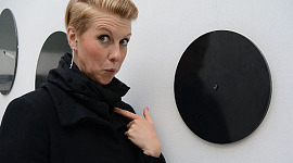 a woman pointing at herself with a questioning and surprised expression